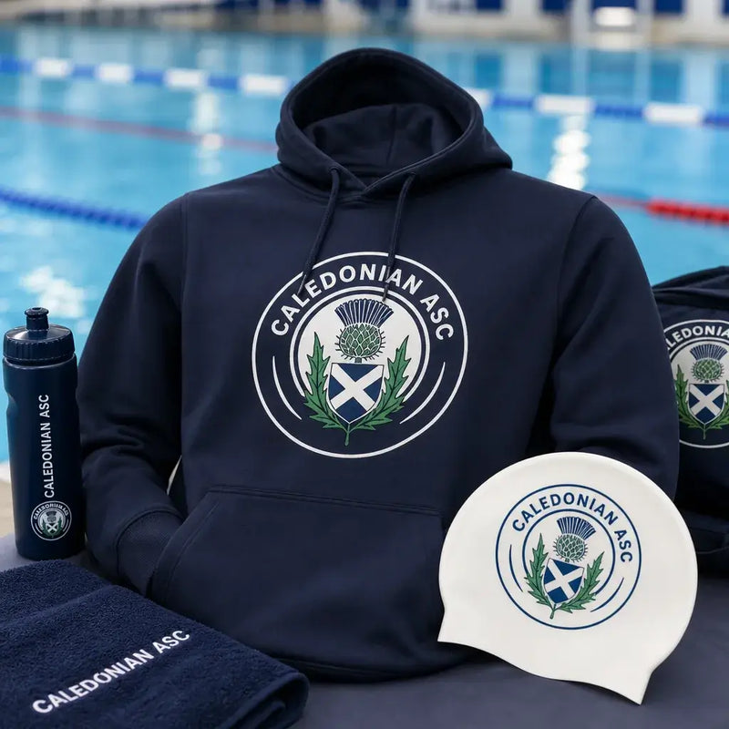Event merchandise hoodie and swim cap with Caledonian ASC crest beside a swimming pool